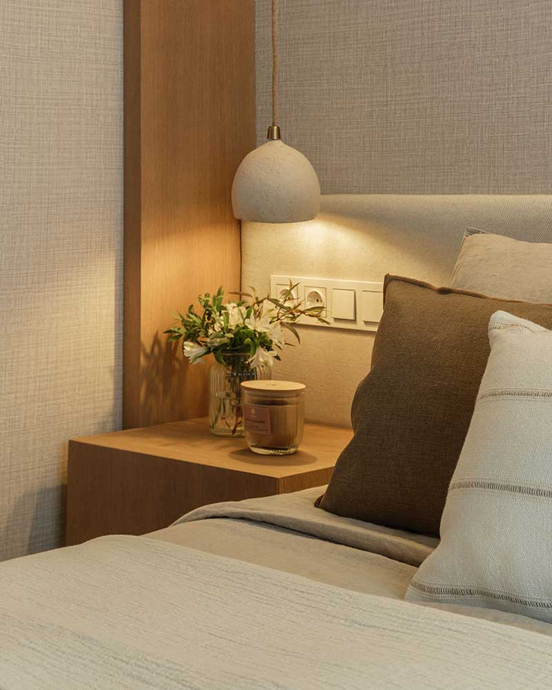 Detalle del dormitorio de Casa Kane con lámpara colgante, mesita de madera y textiles naturales