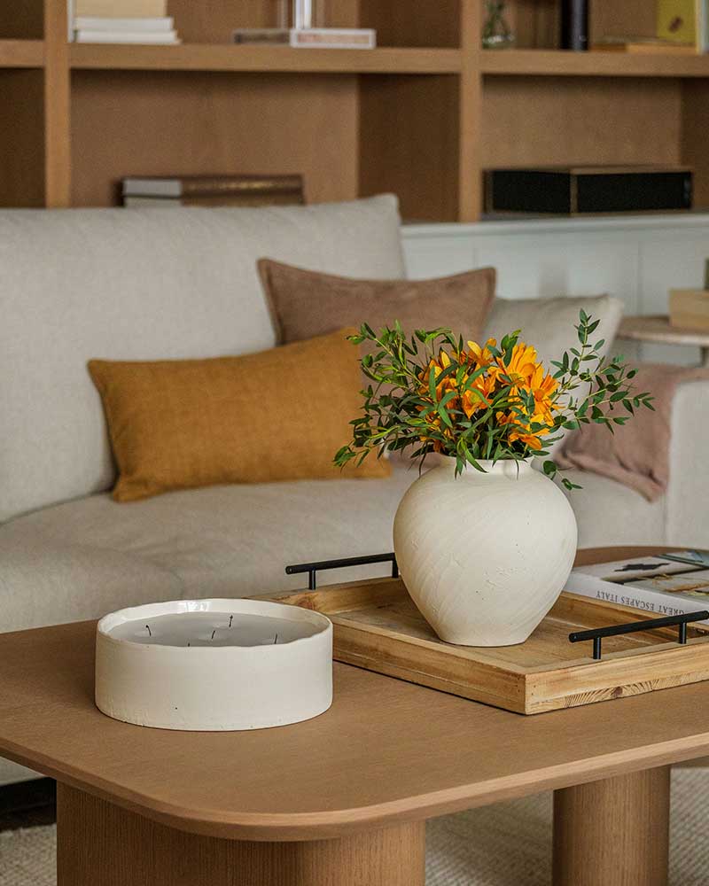 Detalle de mesa de centro de Casa Kane con jarrón, flores y elementos decorativos