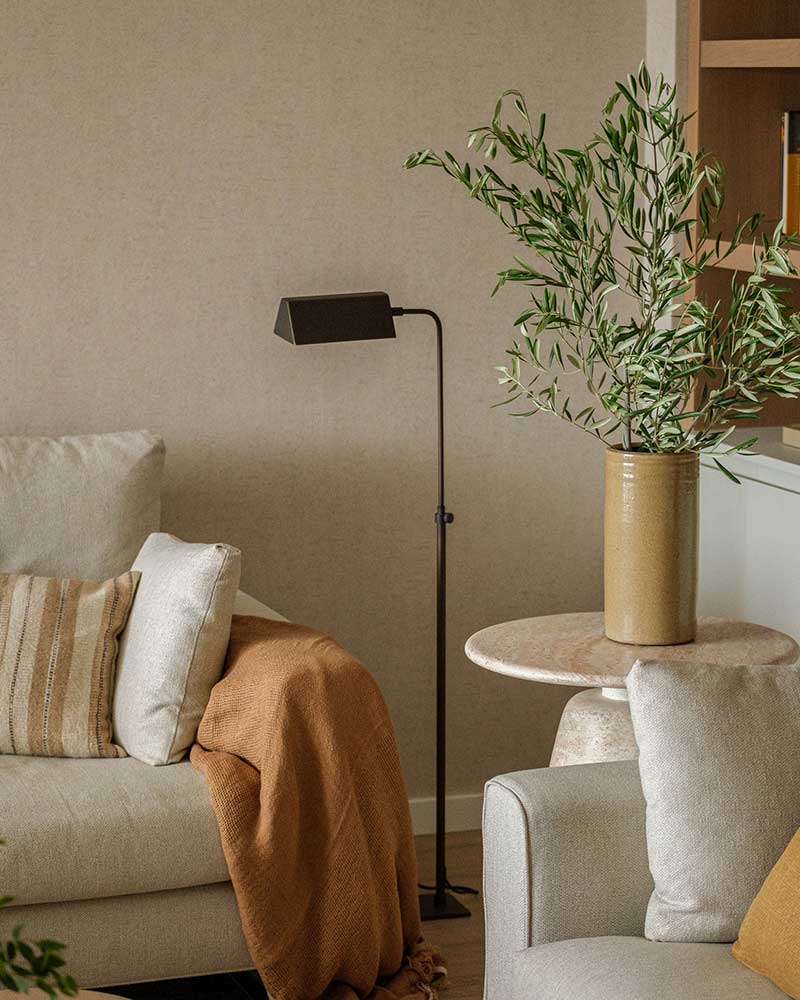 Detalle del salón de Casa Kane con lámpara de pie, sofá y mesa auxiliar