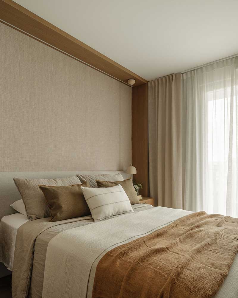 Dormitorio principal de Casa Kane con cabecero textil, madera y cortinas en tonos neutros