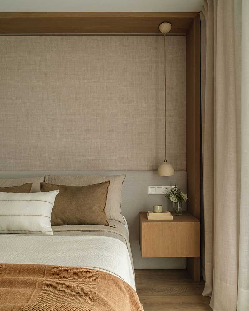 Dormitorio de Casa Kane con cabecero textil, mesita de madera y lámpara colgante