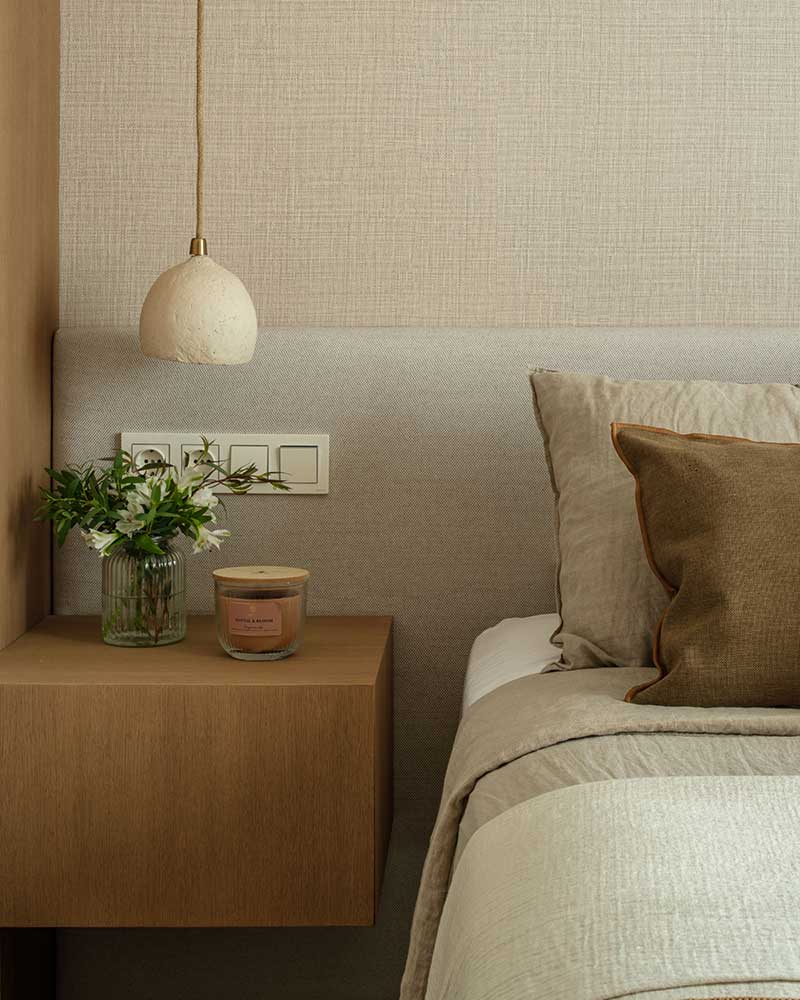 Mesita de noche de madera en el dormitorio de Casa Kane con lámpara y elementos decorativos