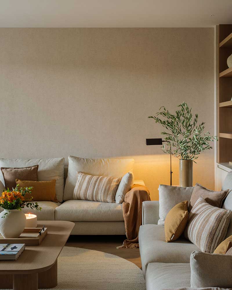 Salón de Casa Kane con sofás, iluminación ambiental y detalles en tonos tierra